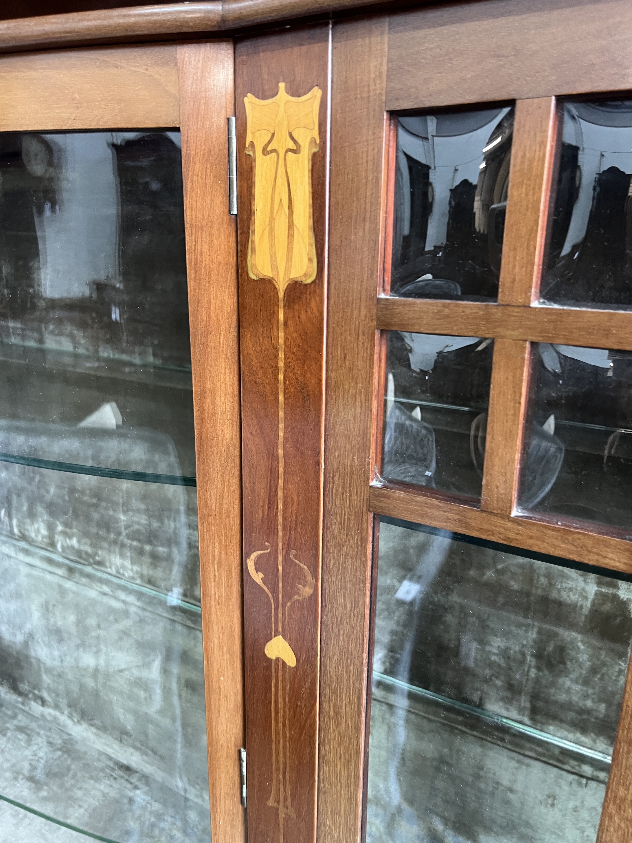 An Arts & Crafts marquetry inlaid mahogany bowfront display cabinet, width 157cm, depth 38cm, height 183cm